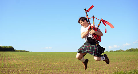 a young man jumping in the air while playing red bagpipes